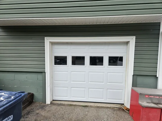 New white raised-panel garage door with windows installed in the same opening