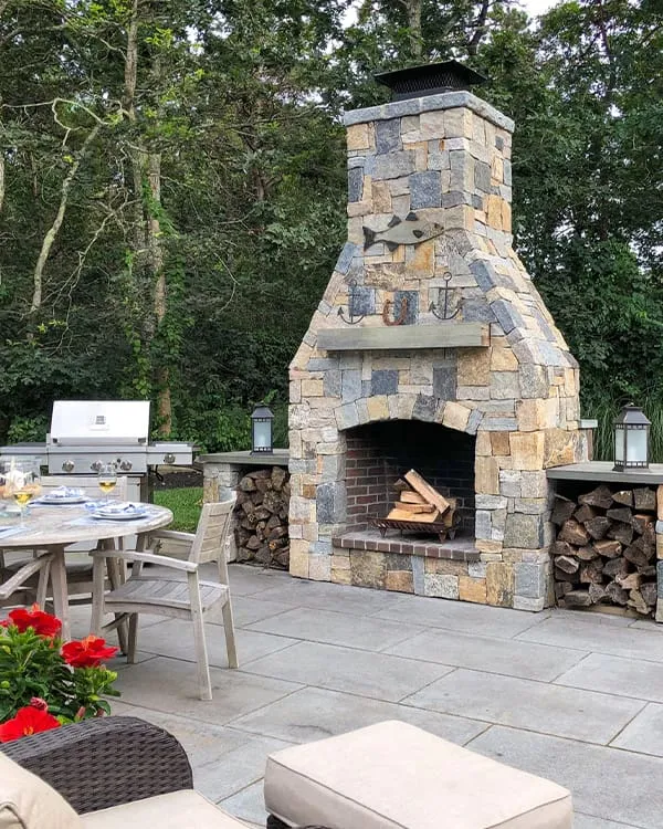 An outdoor fireplace, part of a stunning outdoor kitchen and landscaping project from CMS Landscape.