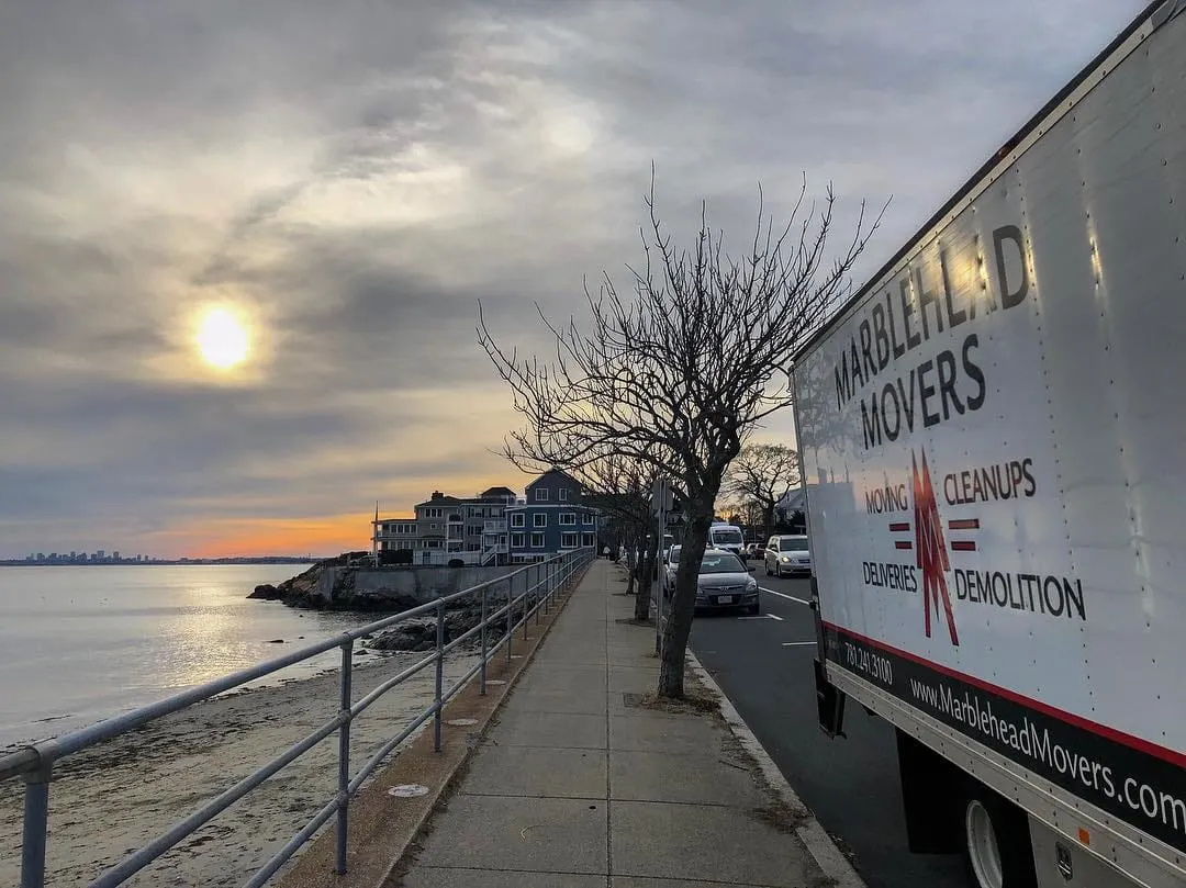 Marblehead Movers truck on the shore road at sunset