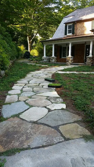 Stone garden path leading to a house porch surrounded by lush greenery