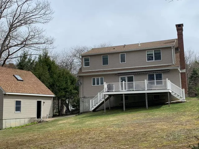 The back of a house with a large deck and stairs.