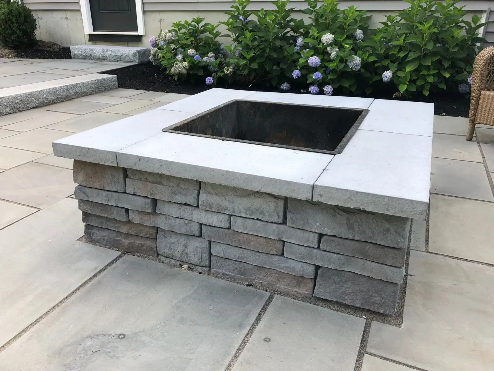 A fire pit is sitting on a patio in front of a house