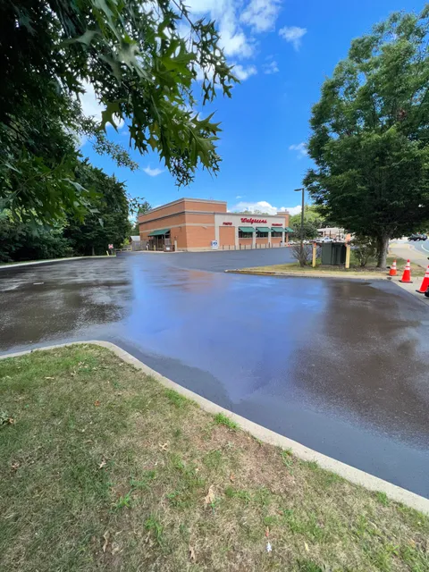 A freshly applied layer of protective jet-black sealcoat curing on a residential driveway in Watertown.
