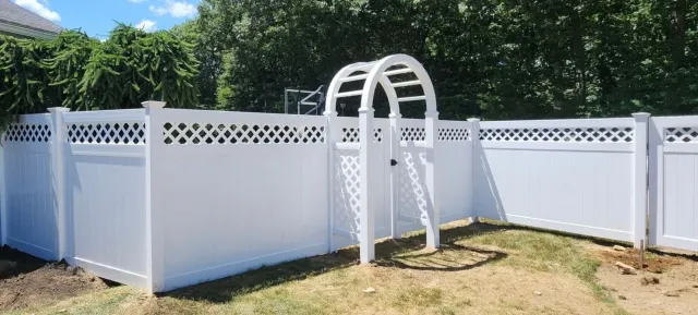 White fenced above-ground pool with a curved metal ladder in a sunny backyard