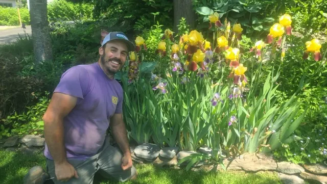 Adom Harnik posing in front of irises in bloom.