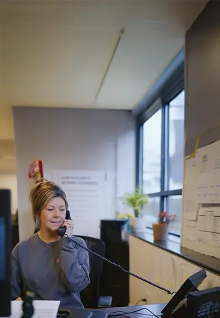 A Door Systems receptionnist sits at a desk on the phone.