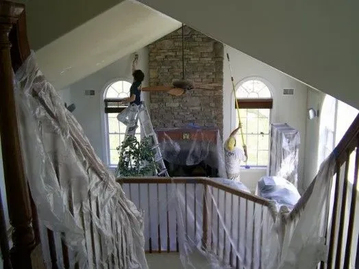 Attic interior with vaulted ceiling, brick chimney, and draped white fabric along a railing