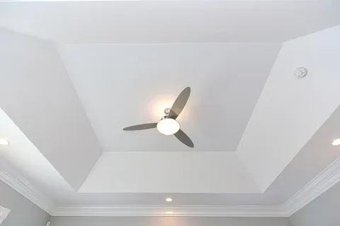 Modern ceiling fan with light on a white tray ceiling
