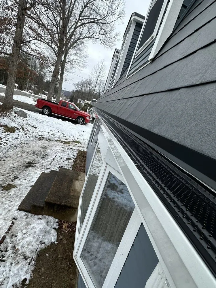 Snow-covered house exterior with a red truck parked along the street