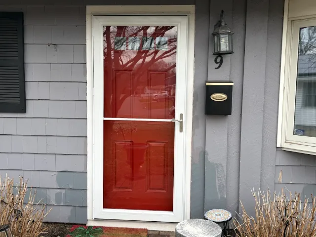 New white storm door installed over a red front door