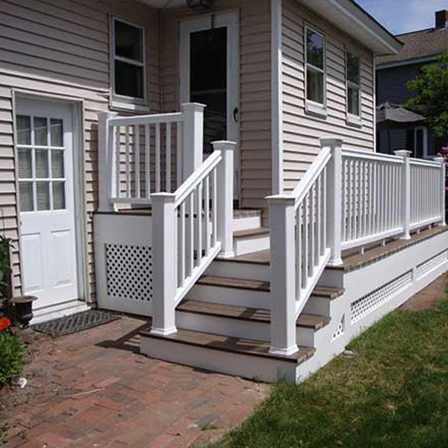 White wooden stairs leading to a back door of a house with beige siding, white trims, and multiple windows.