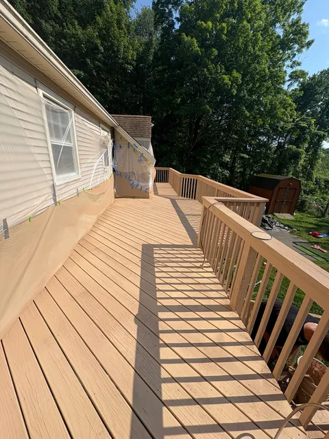 Finished wooden deck walkway and railing alongside a home