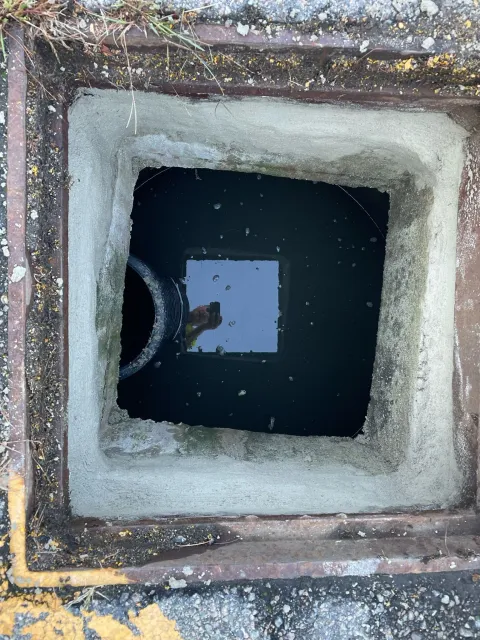A manhole cover with a hole in it and water coming out of it.