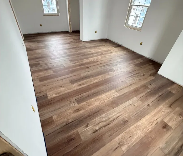Modern interior renovation featuring light brown wood-look luxury vinyl plank flooring in an empty room with white walls.