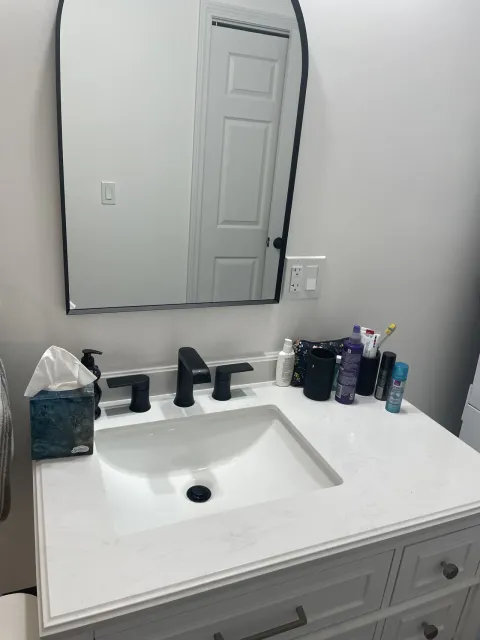 White bathroom vanity with rectangular mirror and dark fixtures