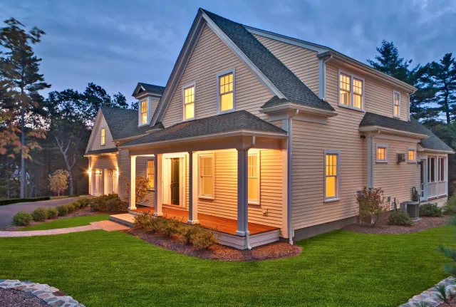 A large house with a porch is lit up at night