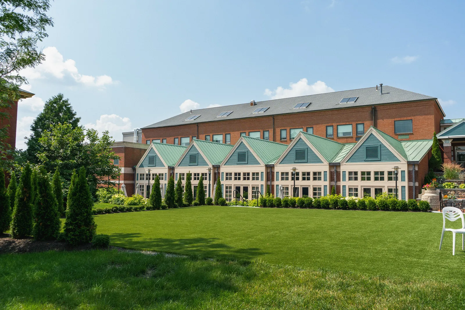 Building with green roofs and large windows facing a manicured lawn under a blue sky.