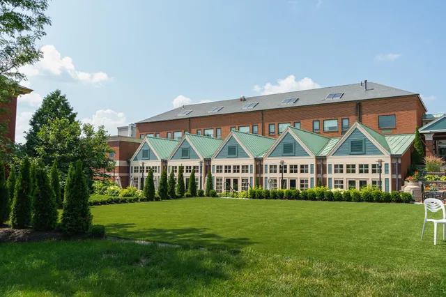 Building with green roofs and large windows facing a manicured lawn under a blue sky.