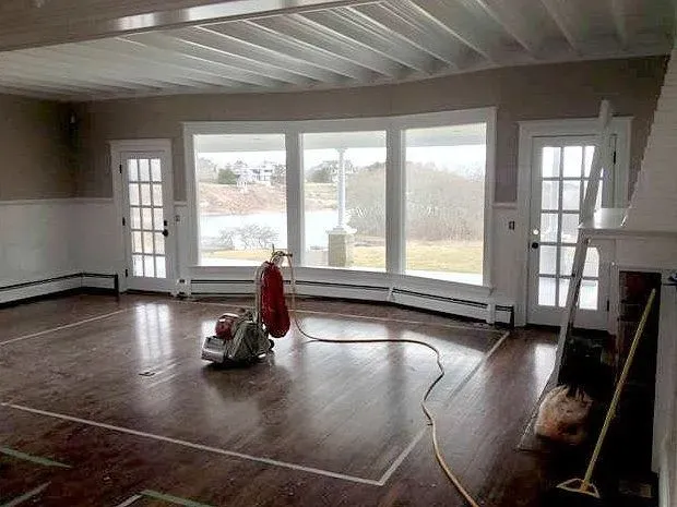 Interior renovation: room with wood floors, bay window, doors, and a floor sander.