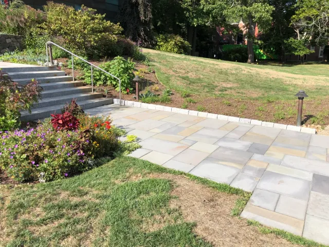 Completed patio and walkway project with stone pavers and landscaped surroundings