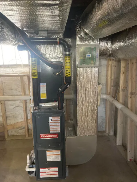 Basement utility room with HVAC ducting, insulated pipes, and a black furnace or air handler unit