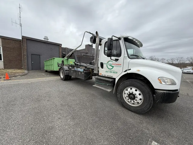 Truck delivering dumpster on scenic property