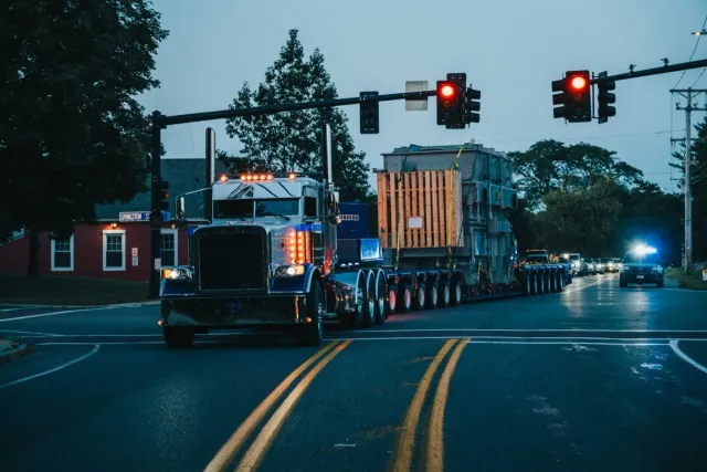 CJ Shaughnessy Peterbilt heavy haul tractor moving a transformer on a multi-axle trailer at dusk