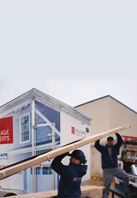 Two installers are loading a truck with a garage door.