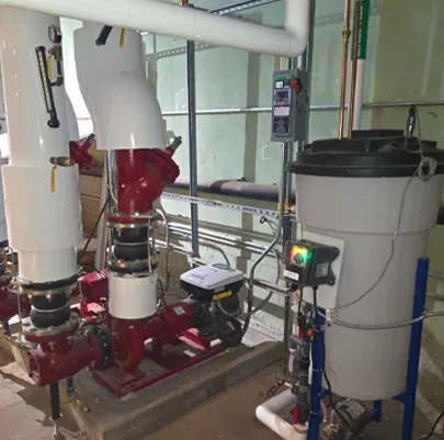 Mechanical room featuring a red commercial pump assembly connected to large white insulated pipes.