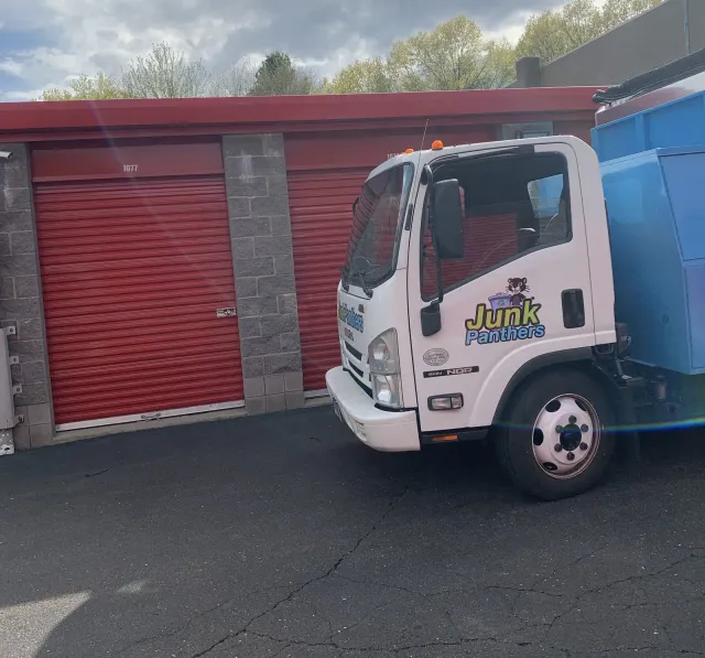 Junk Panthers truck backed up to red storage unit doors