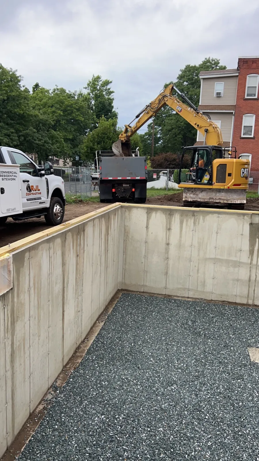 Excavator and RJL dump truck working inside a commercial concrete foundation