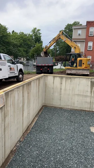 Excavator and RJL dump truck working inside a commercial concrete foundation