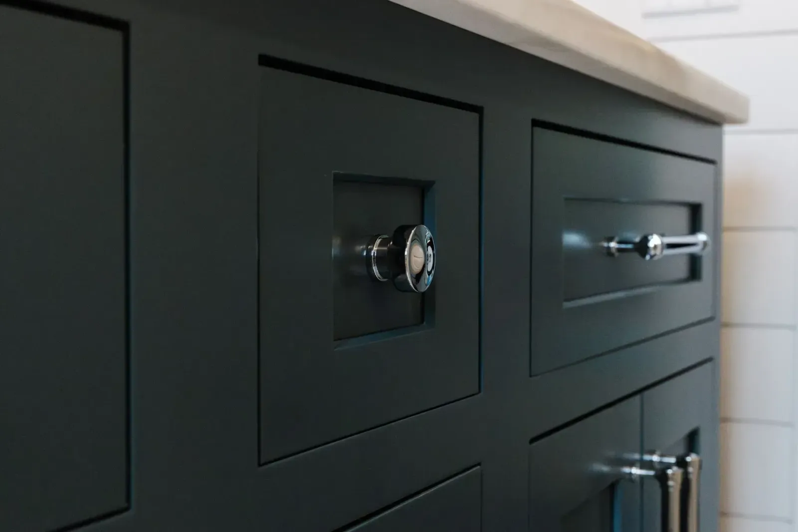 Close-up of a dark kitchen cabinet with chrome drawer and cabinet pulls