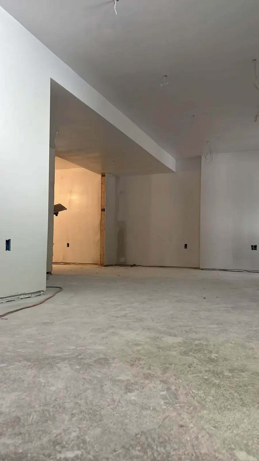A large empty room with white walls and a concrete floor.
