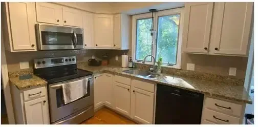 Modern kitchen with stainless steel appliances, cream cabinets, granite counters, and a window over the sink