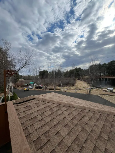 Rooftop view with cloudy sky over a road, trees, and buildings.