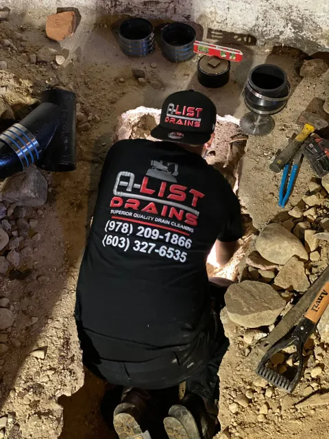 A man is working on a drain in a basement.