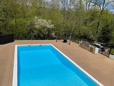 A serene pool surrounded by a wooden deck and a barbecue area, perfect for outdoor relaxation and gatherings.