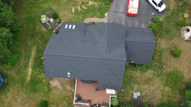 Aerial view of a suburban house with dark gray roof and surrounding garden.