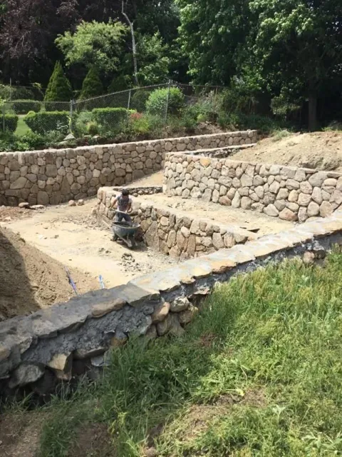 Stone-lined irrigation channel with a small water feature in a green hillside garden