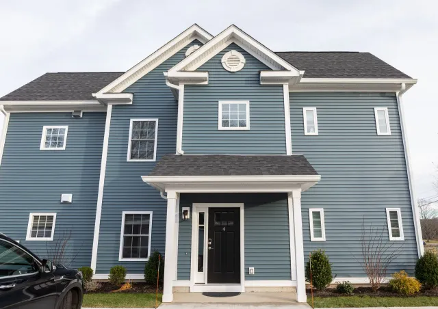 A large blue house with a black car parked in front of it.