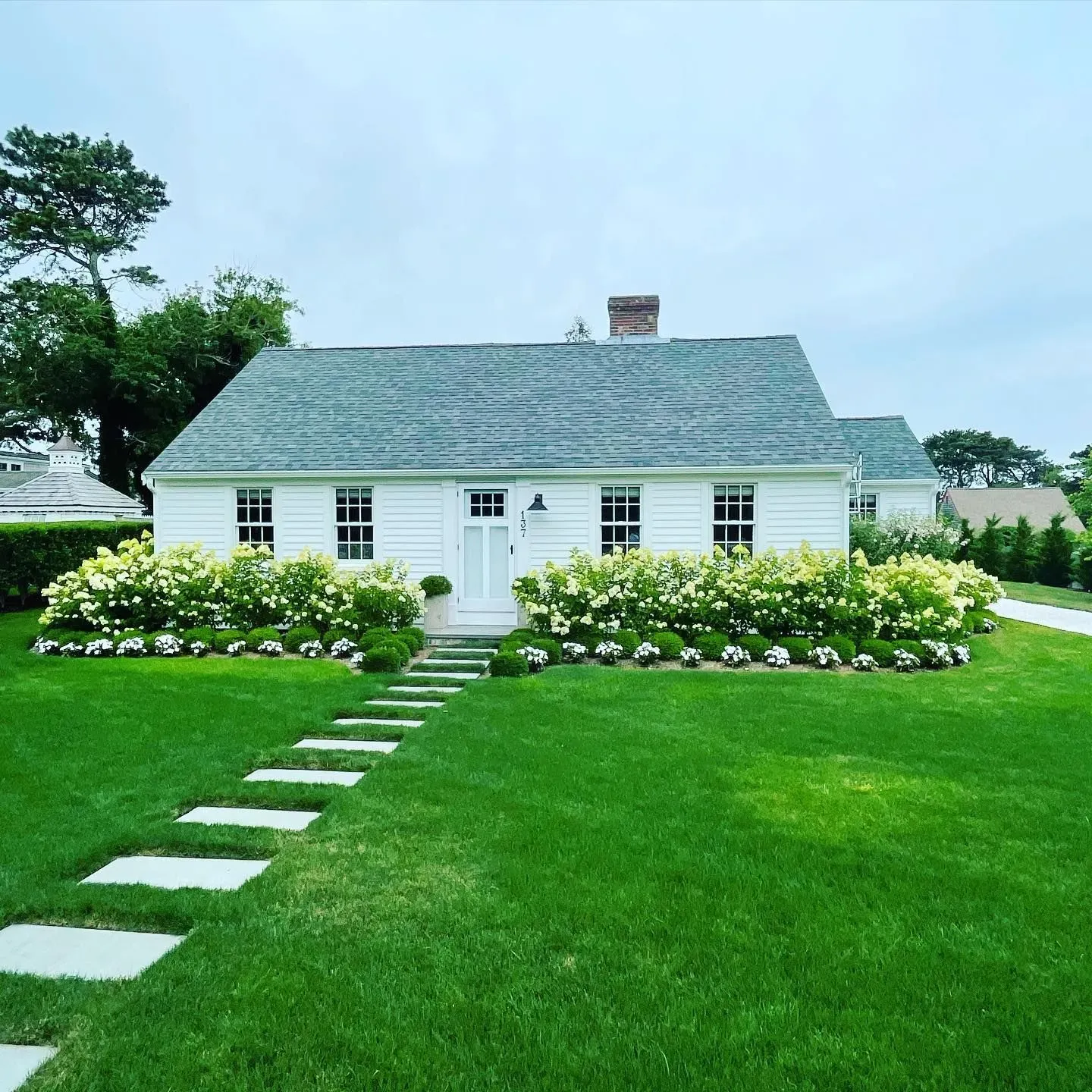 Bright white house with clean windows and beautiful landscaping | Exterior window cleaning Cape Cod