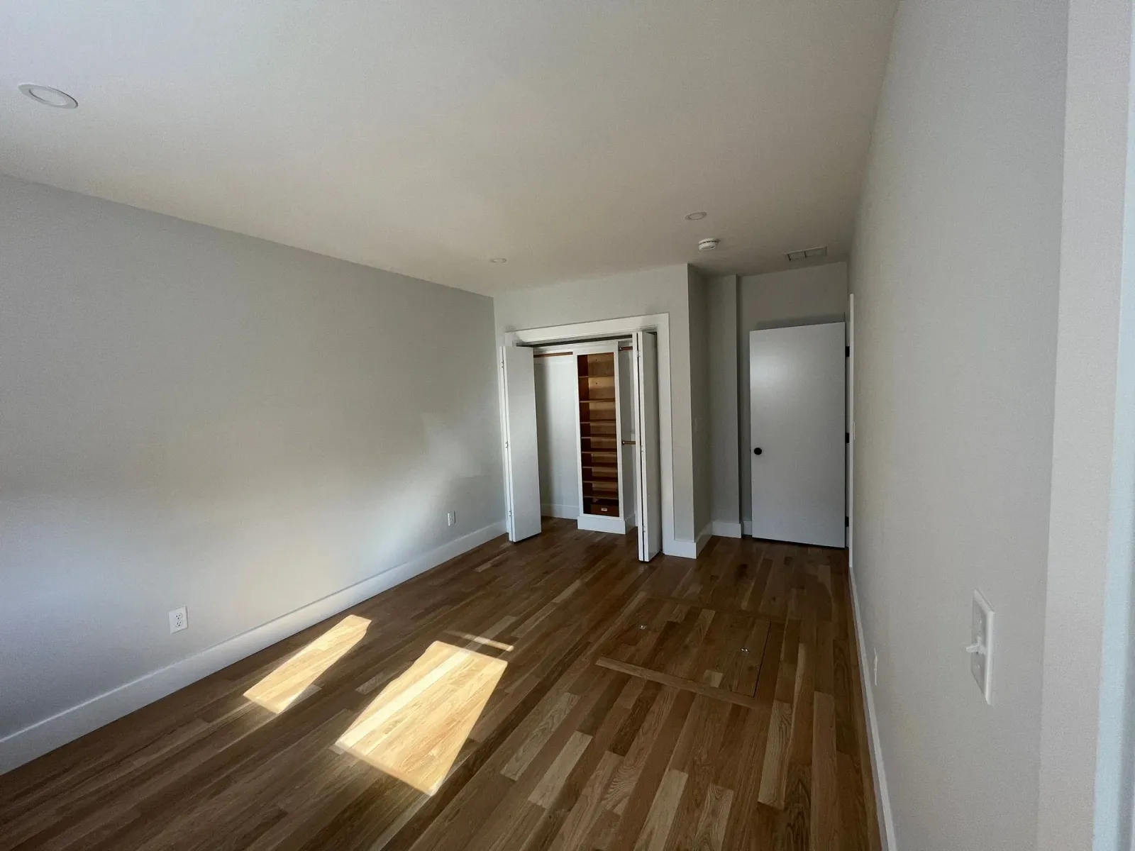 An empty room with hardwood floors and white walls