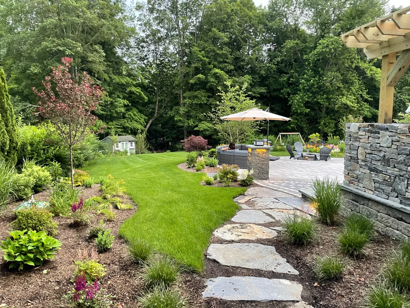 There is a stone walkway leading to a patio in the backyard.
