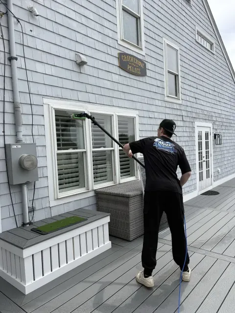 Mass Shine crew member cleaning first floor window with water-fed pole on shingle home South Shore Massachusetts