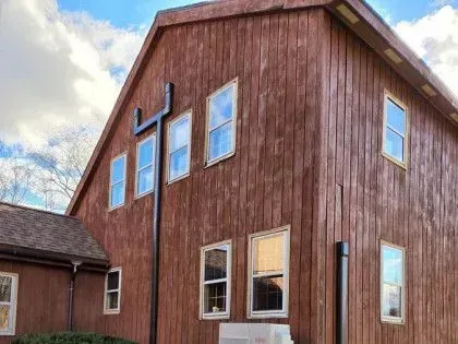 Red barn-style building with a large cross on the side under a cloudy sky