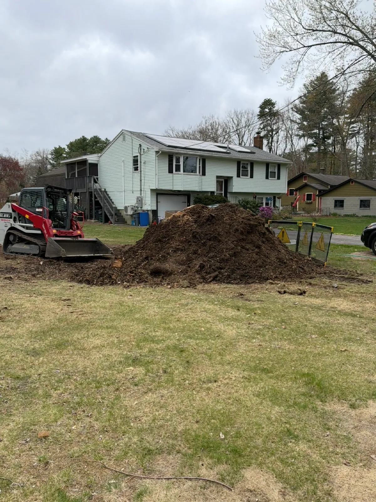 House with construction equipment and dirt pile