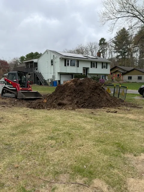 House with construction equipment and dirt pile