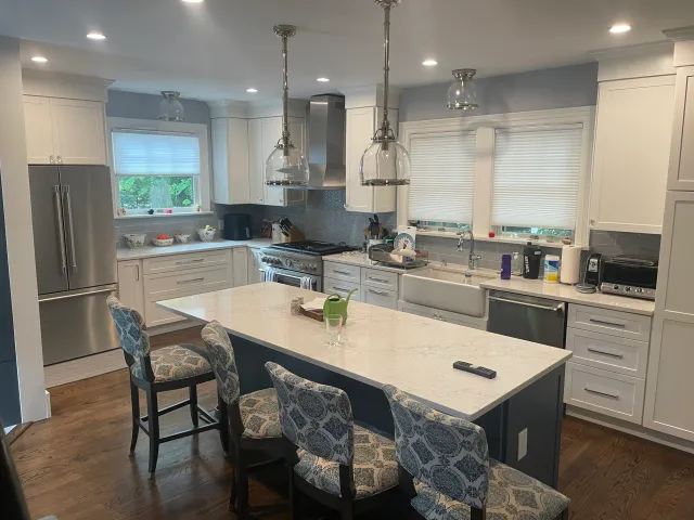 Modern kitchen with white cabinets, marble island, patterned chairs, and stainless steel appliances