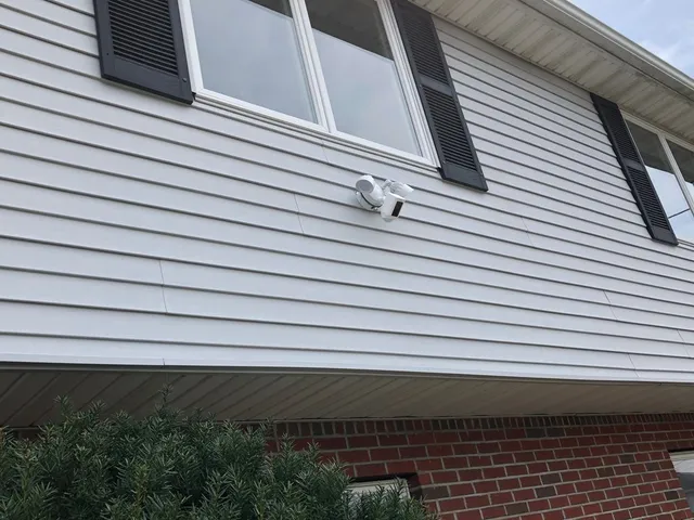 Motion-sensor floodlight mounted on siding